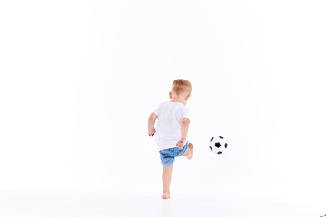 Little cute kid baby boy 3 years old, football fan in white t-shirt playing with soccer ball isolated on white background.  lifestyle concept. Copy space for text