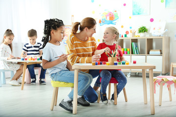 Wall Mural - Children with female teacher at painting lesson indoors