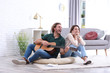 Young man playing acoustic guitar badly for displeased girlfriend in living room. Talentless musician