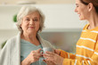 © New Africa - Female caregiver and elderly woman with cup of tea in kitchen