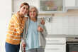 Elderly woman with female caregiver in kitchen. Space for text