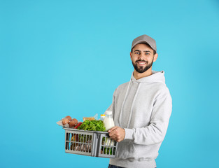 Canvas Print - Man holding basket with fresh products on color background, space for text. Food delivery service