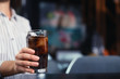 © New Africa - Woman with glass of refreshing cola at table indoors, closeup. Space for text