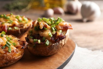 Board of baked potatoes with cheese and bacon on table, closeup