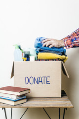 Poster - CLOTHES DONATION AND FOOD DONATION CONCEPT. A man holding a donation box with clothes, shoes and hygiene products.