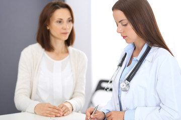 Doctor and  patient  discussing something while standing near reception desk in emergency hospital. Physician at work in clinic. Medicine and health care concept