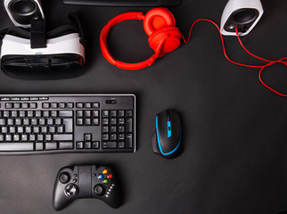 Poster - top view a gaming gear, mouse, keyboard, joystick, headset, vr headset on black table background.