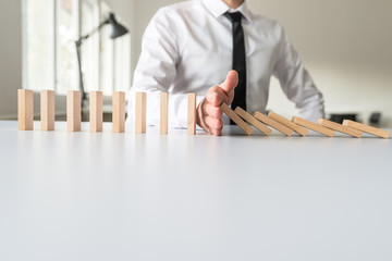 Wall Mural - Businessman intervening to stop falling dominos