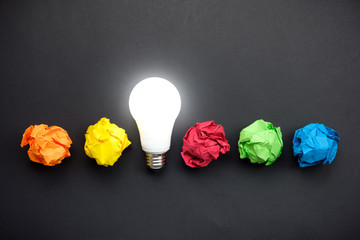 Great idea concept with crumpled colorful paper and light bulb on black background