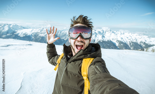 Fotomural Portrait of an andsome man is taking a selfie in the snow on a mountain at winte
