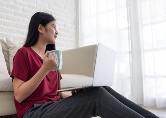 Poster - Asian female freelancer smile and drink coffee with relax emotion and looking out of window at home.working online lifestyle.