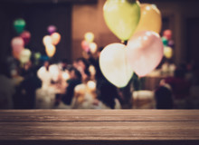 Empty Wooden Counter With Blurred People In The Banquet Room With Colorful Balloon.