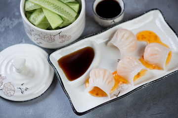 Wall Mural - Steamed chinese prawn hargows with dipping sauces served on a white plate, horizontal shot