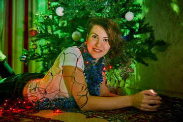 Nice young woman near Christmas tree in the room