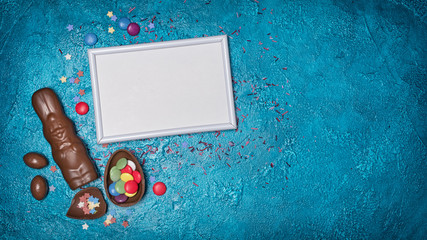 Canvas Print - Mock up of blank white frame with traditional easter sweets as chocolate bunny and eggs