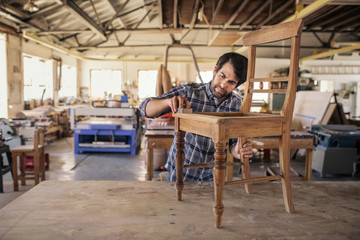 Wall Mural - Furniture maker sanding a chair on workshop bench