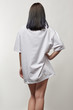 back view of young woman in white oversize t-shirt with copy space isolated on grey