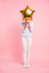 Vertical full length body size view of nice pretty attractive lovely fit slim thin modern girl closing hiding face behind big large air baloon golden star isolated over pastel pink background