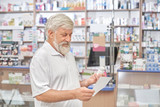 Fototapeta Sawanna - Pensioner looking at prescription in drugstore.