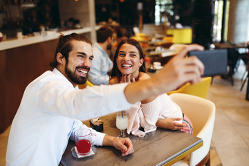 Sticker - Young happy couple at a date making selfie in a coffee shop