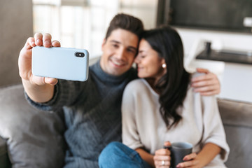 Wall Mural - Happy young couple sitting on a couch at home