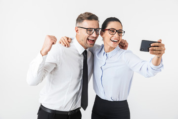 Wall Mural - Young business colleagues couple isolated over white wall background take selfie by mobile phones.