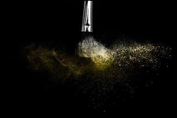 Wall Mural - Cosmetic brush with golden cosmetic powder spreading for makeup artist and graphic design in black background