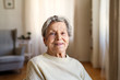 © Halfpoint - A portrait of a senior woman sitting at home, looking at camera.