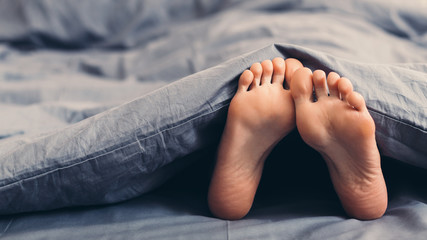 female beautiful feet under blanket in bed