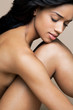© Andreas Kuehn - Naked, young, black woman hugging her knees, portrait.