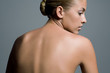 © Andreas Kuehn - Back view of a young woman's naked upper body and her head turned profile.