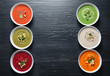 Various soups in bowls and space for text on wooden background, top view. Healthy food