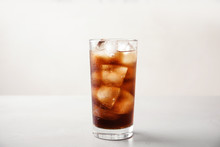 Glass Of Refreshing Cola With Ice On White Table
