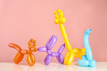 Animal Figures Made Of Modelling Balloons On Table Against Color Background