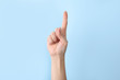 Woman showing number one on color background, closeup. Sign language