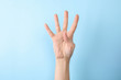 Woman showing number four on color background, closeup. Sign language