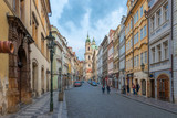 Fototapeta Londyn - Prague, Czech Republic - August 25 2018: Early morning picture of Czech street in downtown Prague with tourists