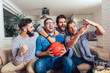 Happy friends or basketball fans watching basketball game on tv and celebrating victory at home.Friendship, sports and entertainment concept.