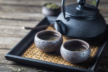 Still-life of japanese healthy green tea in a small cups and teapot over dark background