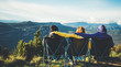 three friends sit in camping chairs on top of a mountain, travelers enjoy nature and cuddle, tourists look into distance on background of panoramic landscape, weekend concept mockup
