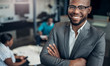 © JonoErasmus - Portrait of a smiling confident black businessman with his arms crossed and all african team in the background