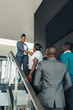 © JonoErasmus - Smiling confident black businesswoman greeting and shaking hands with all african woman on stairs