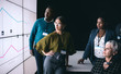 © JonoErasmus - Business team looking at presentation on a digital screen in a dark room