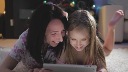 funny mom and lovely daughter are having fun with tablet. happy loving family.