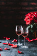 Two wine glasses of rose wine on brick background, bouquet of red roses for romantic evening for Valentines day surprise, marriage proposal passion and love celebration, copy space 