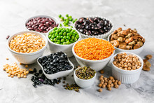 Selection Of Legumes - Beans, Lentils, Mung, Chickpea, Pea In White Bowls On Stone Background