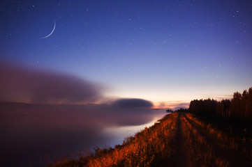 Wall Mural - waxing crescent moon above misty river scenery.