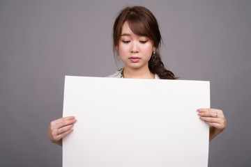 Asian woman holding empty white board with copyspace