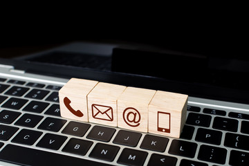 Fototapete - Wood block symbol telephone, mail, address and mobile phone on laptop keyboard. Website page contact us or e-mail marketing concept