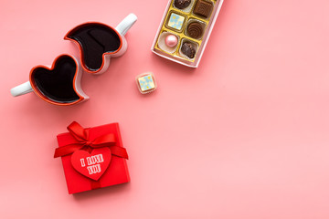 Valentine's day concept. Sweets, red gift box, heart-shaped mugs on pink background top view space for text